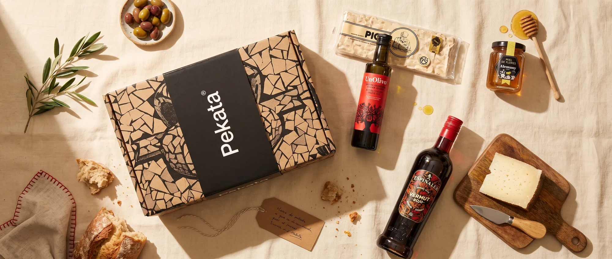 Pudełko paczki świątecznej Pekata z ręcznie robionym turronem, miodem, oliwą i wermutem na stole